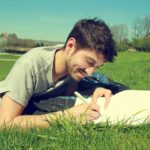 芝生で執筆する男性